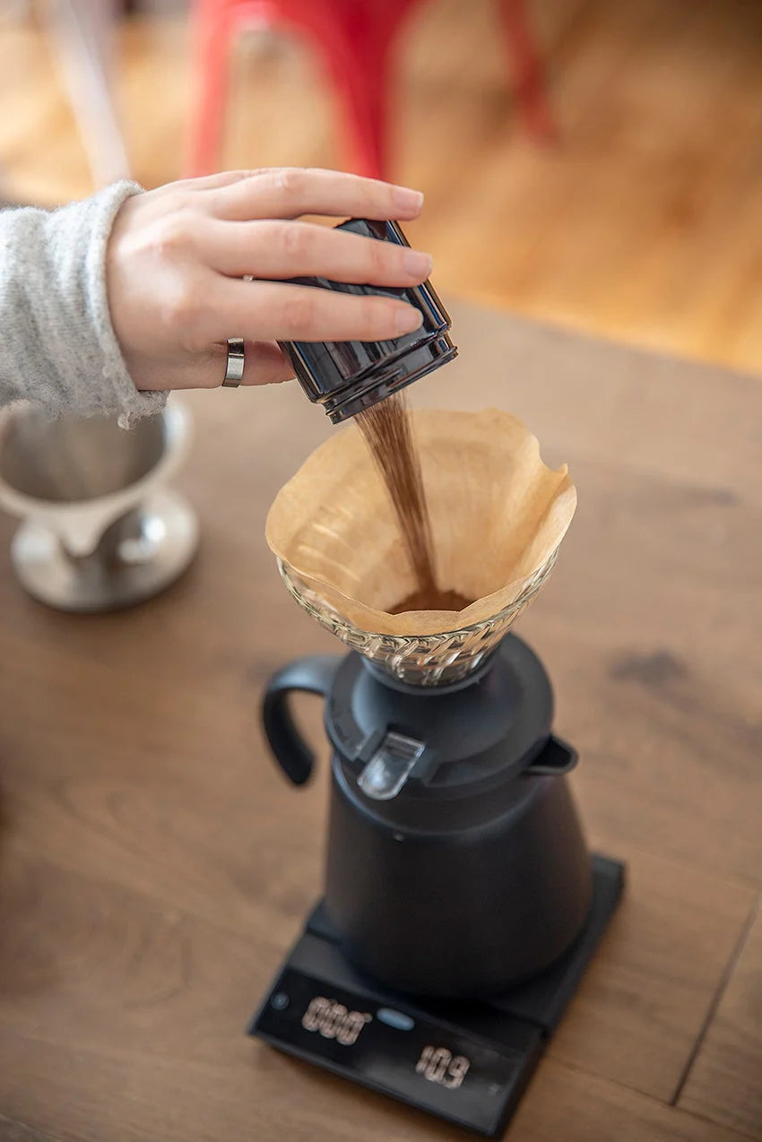 Person adding coffee to a V60 dripper